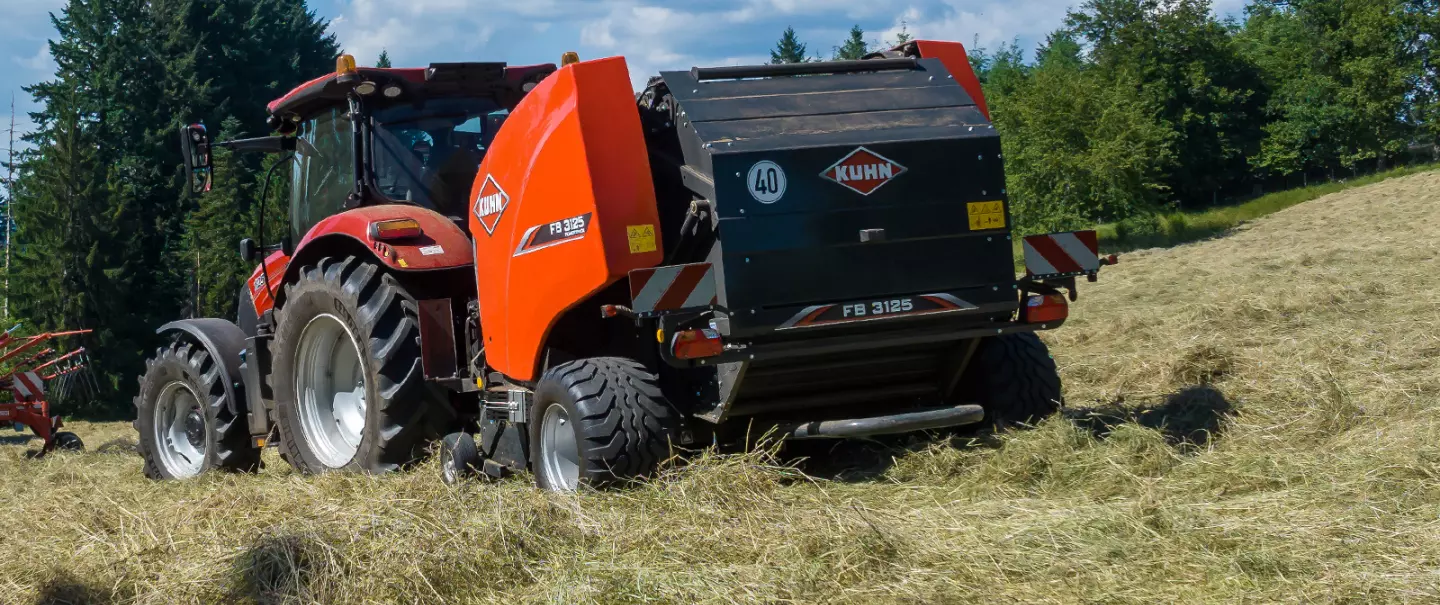 Rotoempacadora de cámara fija FB 3125 de KUHN y, al fondo, el operador en el campo