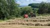 La rotoempacadora de cámara fija FB 3125 de KUHN empaca pacas redondas de ensilado en un campo con grandes hileras